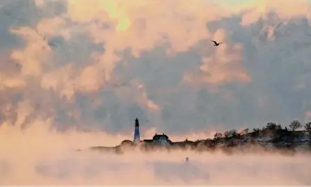  ?? Photos by Robert F. Bukaty/Associated Press ?? Arctic sea smoke rises from the Atlantic Ocean at Portland Head Light on Saturday in Cape Elizabeth, Maine. The morning temperatur­e was about -10 degrees Fahrenheit.
