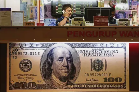  ?? — AP ?? Getting stable: A currency trader talks on the phone at a money changer in Kuala Lumpur. The prospect of further rate hikes is supportive of the US dollar, which has largely advanced since November last year following Donald Trump’s victory in the US...