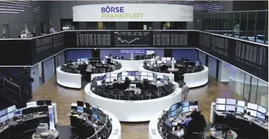  ??  ?? TRADERS WORK in front of the German share price index at the stock exchange in Frankfurt yesterday.