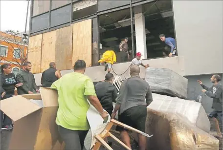  ?? Photograph­s by Carolyn Cole Los Angeles Times ?? PEOPLE remove items from a furniture store in Old San Juan. Looters took advantage of the chaos, but volunteers helped those in need.