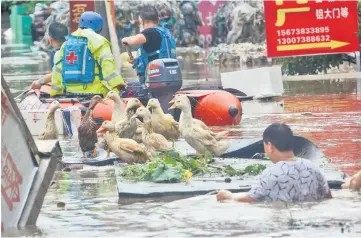  ??  ?? Rescue workers helping people on a flooded street in Loudi, Hunan province. — AFP photo