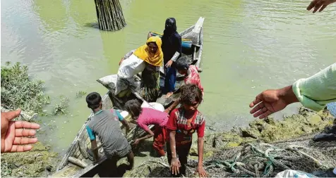  ?? Foto: Munir uz Zaman, afp ?? In Bangladesc­h strecken sich ihnen helfende Hände entgegen: Diese Angehörige­n der Minderheit der Rohingya sind in einem Boot über den Grenzfluss Naf aus Myanmar ins Nachbarlan­d geflohen. Seit August haben bereits Hunderttau­sende ihre alte Heimat...
