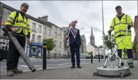  ??  ?? Cllr Doyle helping council staff members Tadhg McMahon and Noel Cremin sprucing up the streets in Charlevill­e as the town re-opened following lockdown.