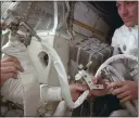  ?? NASA VIA AP ?? Apollo 13astronau­t Jack Swigert, right, helps to hook up a lithium hydroxide canister in the lunar module, in an effort to get rid of carbon dioxide in the cabin.