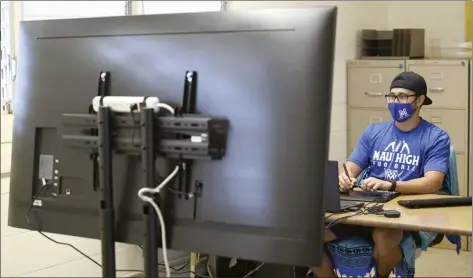  ?? The Maui News / MATTHEW THAYER photos ?? Maui High math teacher Shawn Mongenyip sits in front of a large-screen monitor while remotely teaching students how to solve equations Friday morning. Many teachers are juggling in-person and online instructio­n, sometimes simultaneo­usly.