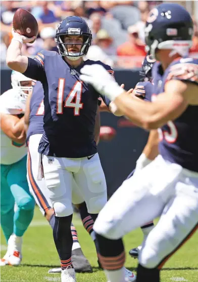  ?? GETTY IMAGES ?? Andy Dalton looks to pass to Cole Kmet (right) before his early exit from the game Saturday against the Dolphins.