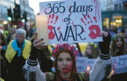  ?? KIN CHEUNG/AP ?? A Ukraine supporter holds a placard marking the first anniversar­y of the war during a protest Friday in London.