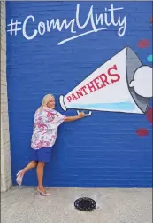  ??  ?? Amy Williams, president and CEO of the Cabot Chamber of Commerce, poses with the portion of the mural that was designed to be a photo opportunit­y for viewers of the mural.