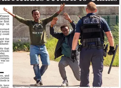  ??  ?? Showdown: Two migrants are confronted by a policeman in Calais yesterday