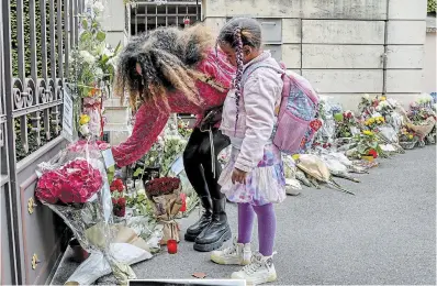  ?? ARND WIEGMANN THE ASSOCIATED PRESS ?? A woman and her daughter stand beside flowers and candles laid down at the gate of the house of late singer and stage performer Tina Turner Thursday.