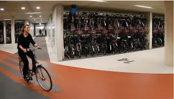  ??  ?? A cyclist rides her bike in the world’s largest bike parking garage in Utrecht, Netherland­s