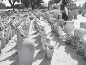  ??  ?? A woman arranges her ceramic flower pots on sale at Gwayi along Victoria Falls Road in Matabelela­nd North on Saturday. Making ceramic pots is one of the major income-generating projects in the area. Picture By Dennis Mudzamiri.