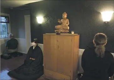  ?? Jae C. Hong Associated Press ?? RESIDENT PRIEST Genmyo Jana Zeedyk, second from left, and other members of the Anchorage Zen Community sit in silence in their meditation hall, or zendo, during a Sunday service in Anchorage last month.