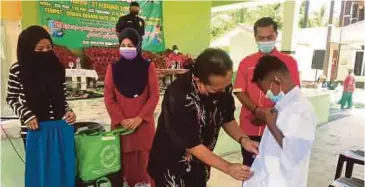  ?? (Foto Hazira Ahmad Zaidi/bh) ?? Pengerusi Yayasan Amal Dato’ Zul Wisma, Datuk Dr Zulkepli Mohamad memakaikan baju sekolah kepada Muhd Amirul Zafran pada Program Back To School 2021 di Seterpa, Peringat, Kota Bharu, semalam.