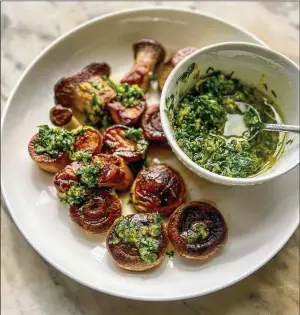  ?? VIRGINIA WILLIS FOR THE AJC ?? King trumpet and white button mushrooms, seared to a dark golden brown, are topped with zesty lemon gremolata, with a bowl of the garlicky, herby sauce on the side.