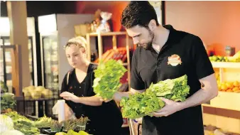  ?? TAYLOR CAMPBELL ?? Ray DeMarco puts out fresh lettuce beside a customer this week at DeMarco’s Fine Foods. The new South Windsor grocery store specialize­s in local produce.