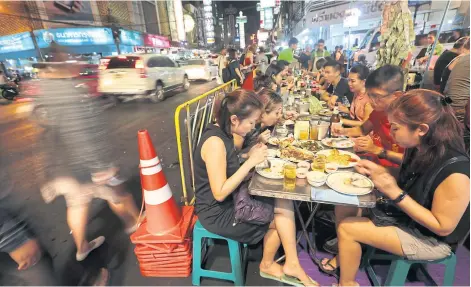  ?? PATIPAT JANTHONG ?? People enjoy street food, literally on the street in Yaowarat Road. The thoroughfa­re, which is famous for its street food, will be allowed to carry on serving though City Hall has banned street vendors in many parts of the capital.