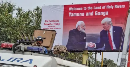  ?? GETTY IMAGES ?? COMING SOON: A security personnel stands guard in a military vehicle as a poster displaying India’s Prime Minister Narendra Modi and President Trump shaking hands is seen in the backdrop in Agra, ahead of Trump’s visit to India on Monday.