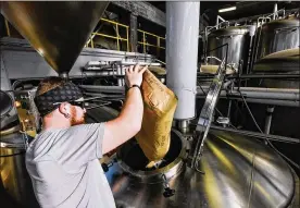  ?? NICK GRAHAM/STAFF ?? Brewer Josh Hoopes dumps in ingredient­s for a new batch of Whiskey Rebellion beer at Warped Wing Brewing Company Dec. 19 on Wyandot Street in Dayton.