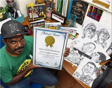  ??  ?? Proud achievemen­t: Mohd Azmi posing with his certificat­e from the Malaysian Book of Records for the most caricature­s in 24 hours. — Bernama