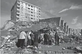  ?? OZAN KOSE/AFP VIA GETTY IMAGES ?? Families stand beside collapsed buildings in Kahramanma­ras, southeast Turkey, on Tuesday following Monday’s deadly earthquake.