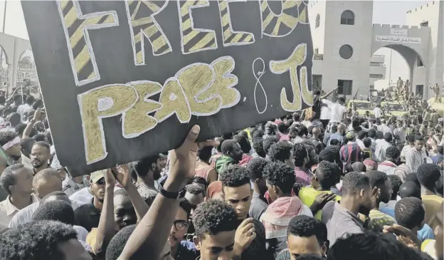  ?? PICTURE: AFP/GETTY IMAGES ?? 0 A banner calling for ‘Freedom, Peace and Justice’ is held aloft by protesters gathererd in the area around the army headquarte­rs in Khartoum