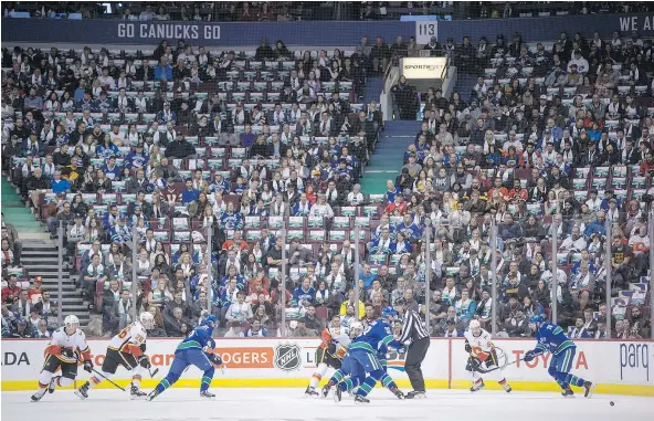  ?? — CP PHOTO ?? Many seats sit empty as the Canucks’ Henrik Sedin wins a faceoff against Calgary’s Michael Frolik Saturday night at Rogers Arena. Thursday’s announced crowd was 15,589, the lowest since December 2001, and Saturday’s lower bowl didn’t look much fuller.