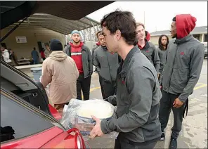  ?? NWA Democrat-Gazette/ANDY SHUPE ?? Members of the Arkansas football team unload food before helping serve a meal Thursday at the 7hills Homeless Center in Fayettevil­le. Players served food at several locations in Northwest Arkansas.