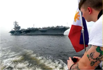  ?? AP FOTO ?? PATROL: A US sailor takes a photograph of the aircraft carrier USS Ronald Reagan as it anchors off Manila Bay for a goodwill visit.