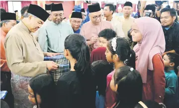  ??  ?? Ahmad Zahid (left) giving out ‘duit raya’ to children during a get-together in conjunctio­n with Aidiladha at the General Operations Force North Brigade, Special Operations Force Commando 69 and Ulu Kinta GOF Training Centre. — Bernama photo