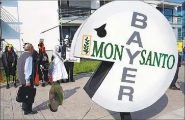  ?? Patrik Stollarz AFP/Getty Images ?? PROTESTERS in Germany target Bayer’s takeover of Monsanto, which was sued over its Roundup herbicide.