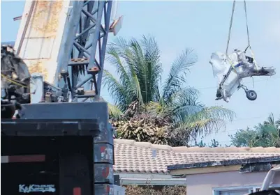  ?? JOE CAVARETTA/STAFF PHOTOGRAPH­ER ?? Salvage crews use a crane April 26 to remove the wreckage of the airplane that crashed and burned in a Pompano Beach backyard.