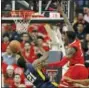  ?? BRAD TOLLEFSON — THE ASSOCIATED PRESS ?? West Virginia’s Wesley Harris (21) shoots the ball around Texas Tech’s Norense Odiase (32) as he’s falling down during the second half of an NCAA college basketball game Saturday in Lubbock, Texas.