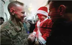  ??  ?? QARAQOSH, Iraq: A US soldier shakes hands with an Iraqi boy during a Christmas Eve service at the Saint John’s (Mar Yohanna) church in this town (also known as Hamdaniya), 30 km east of Mosul, yesterday. —AFP