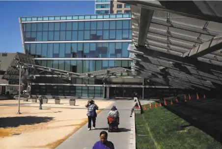  ?? Leah Millis / The Chronicle 2017 ?? Above: People pass by the “stark, sketchy void” of the plaza outside of the futuristic S.F. Federal Building. Below: The federal building in Oakland that opened in 1993 is an example of government architectu­re that pulls historic elements into its design.