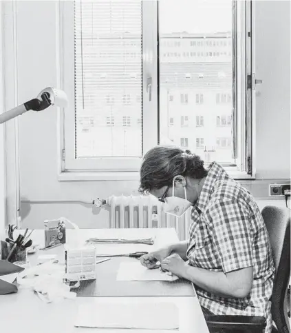  ?? MUSTAFAH ABDULAZIZ PHOTOS/THE NEW YORK TIMES ?? Ruth Zimmermann, an archivist, applies tape to the back of a file last month in Berlin. Researcher­s are working to reassemble millions of pieces of paper that were torn up by the Stasi in the final days of the German Democratic Republic.