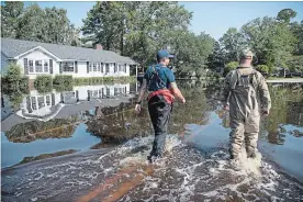  ?? SEAN RAYFORD GETTY IMAGES ?? U.S. Coast Guard Chief Lorenzo Ladaga, left, and Chris Blanchette survey floodwater­s caused by hurricane Florence near the Crabtree Swamp on Friday in Conway, S.C.