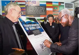  ??  ?? By HANIS ZAINAL haniszaina­l@thestar.com.my
A new chapter: Dr Koroma (right) signing a plaque to mark the opening of Limkokwing University of Creative Technology’s campus in Freetown. Looking on are
Lim (centre) and Bell.