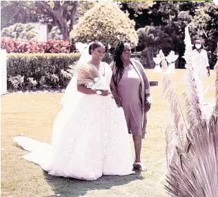  ?? ?? The beautiful bride is escorted up the aisle by her mother, Blossom Bent.