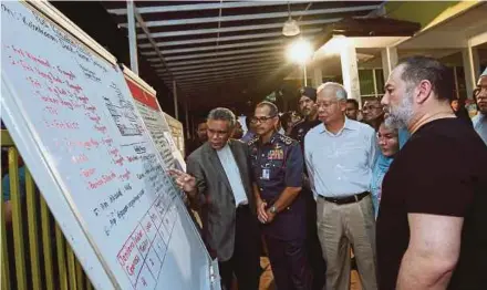  ?? BERNAMA PIC ?? Yang di-Pertuan Agong Sultan Muhammad V (right) listening to a briefing during his visit to the Darul Quran Ittifaqiya­h tahfiz school in Kampung Datuk Keramat, Kuala Lumpur, yesterday. With him are Prime Minister Datuk Seri Najib Razak and his wife,...