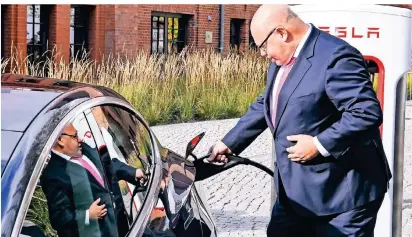  ?? FOTO: DPA ?? Bundeswirt­schaftsmin­ister Peter Altmaier (CDU) greift am Donnerstag bei der Vorstellun­g einer Tesla-ladestatio­n der neuesten Generation auf dem Gelände vom Euref-campus Berlin zum Ladekabel.