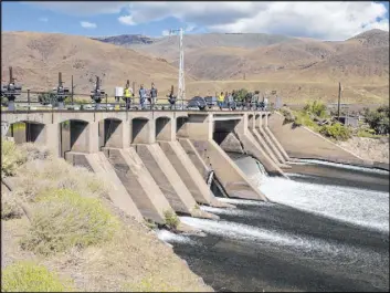  ?? Scott Sonner The Associated Press ?? Federal officials walk across the Derby Dam in Wadsworth, located about 20 miles east of Reno, as Truckee River water flows beneath it on Sept. 11.