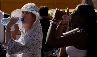  ?? ?? Des touristes sirotent de l'eau fraîche alors qu'ils s'abritent d'une chaude après-midi ensoleillé­e près du Colisée de Rome, le 5 juillet 2023\.