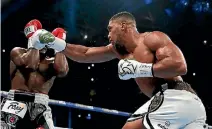  ?? PHOTO: REUTERS ?? Anthony Joshua, right, has Carlos Takam on the ropes in Cardiff as he defends his heavyweigh­t titles.