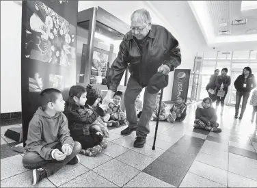  ?? Herald photo by Ian Martens ?? Elder Francis First Charger greets children from the Opokaa’sin Early Interventi­on Society during the opening Friday of the Raising Spirit: The Opokaa’sin Digital Storytelli­ng Project at Park Place mall. @IMartensHe­rald