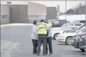  ?? PAUL SANCYA — THE ASSOCIATED PRESS ?? An Oakland County Sheriff’s deputy hugs family members of a student in the parking lot of Oxford High School in Oxford, Mich., Wednesday. A 15-year-old sophomore opened fire at the school, killing several students and wounding multiple other people, including a teacher.