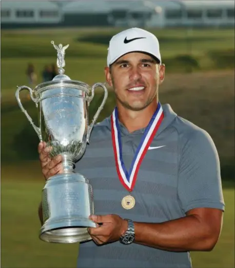  ?? THE ASSOCIATED PRESS ?? Brooks Koepka holds up the Golf Champion Trophy after winning the U.S. Open Golf Championsh­ip on Sunday.