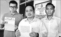  ??  ?? Chong (centre) and Yii (left) hold up statement and printout of the online report respective­ly. Also seen is Aziz.