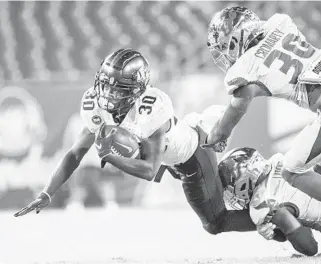  ?? WILLIEJALL­ENJR/ ORLANDOSEN­TINEL ?? UCFrunning back Greg McCrae is tackled bySouth Florida defensive back Mekhi LaPointe (22) and defensive back Isaiah Cromarty on Friday inTampa.