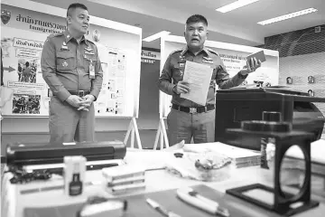  ??  ?? Vongpint (right) holds a fake Singaporea­n passport during a press conference in Bangkok.